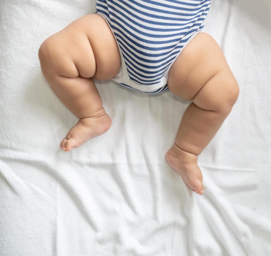 barnets fötter i en vit säng foto