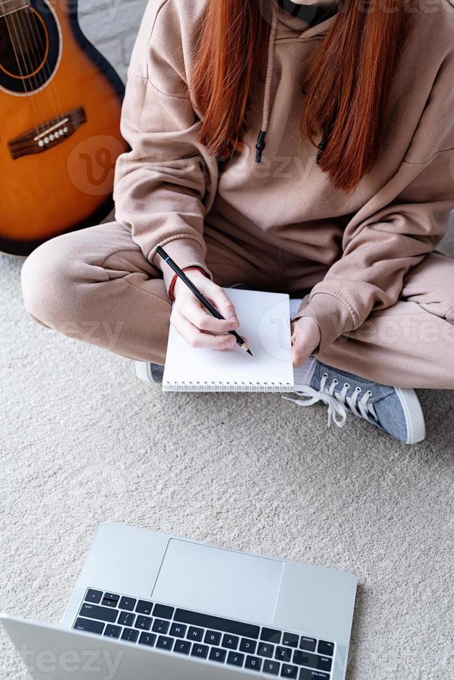 ung kvinna inlärning till spela gitarr på Hem foto