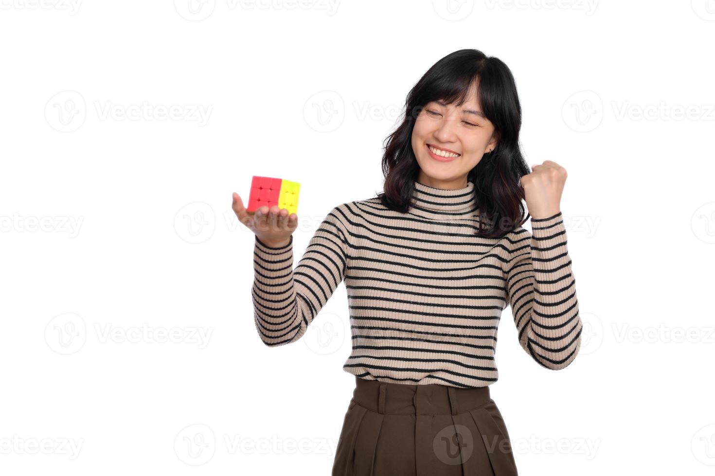 asiatisk kvinna innehav en rubik kub stående på vit bakgrund. lösning kubisk problem, problem lösning och framställning strategisk rör sig begrepp foto