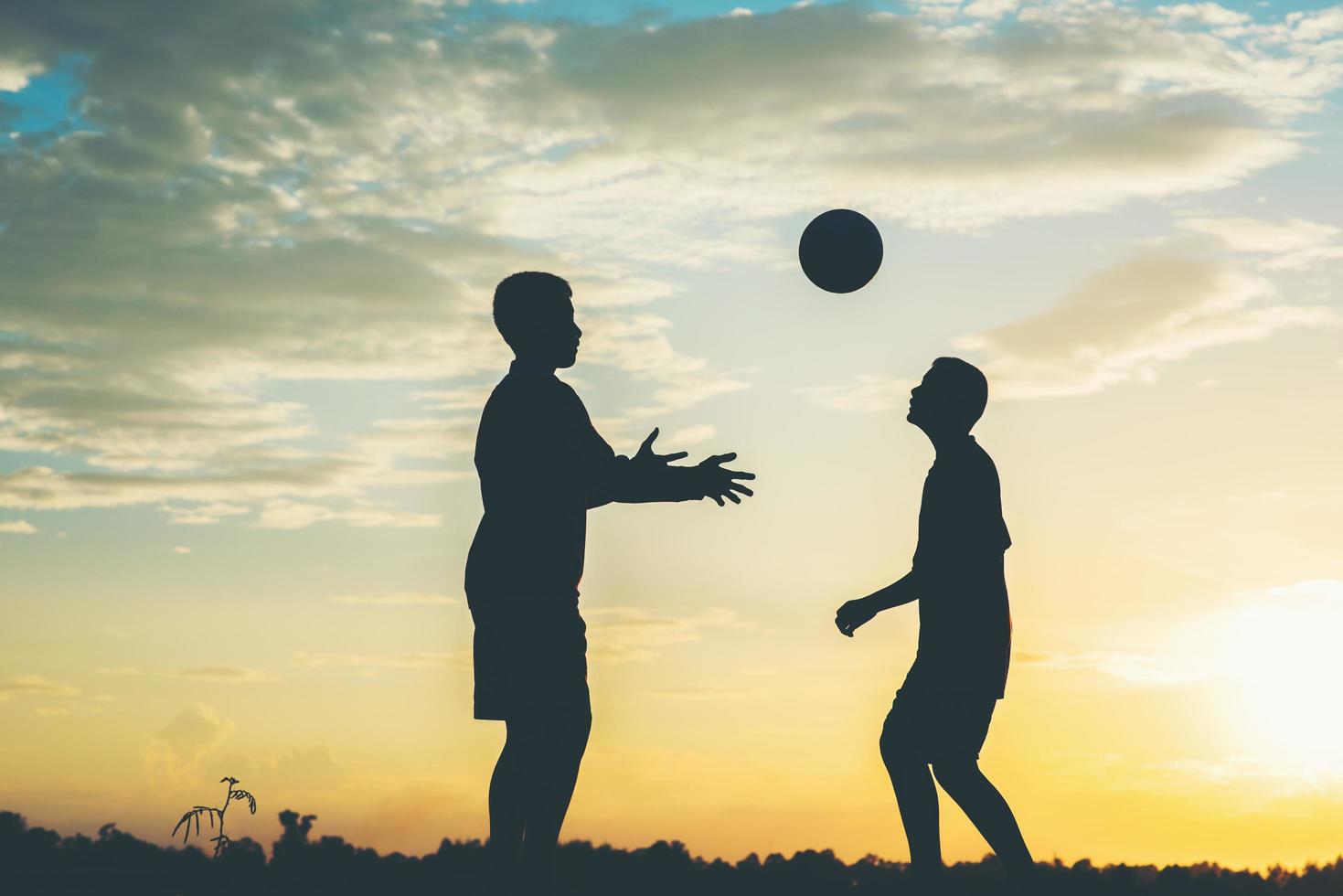 silhuett av barn som spelar fotboll fotboll foto