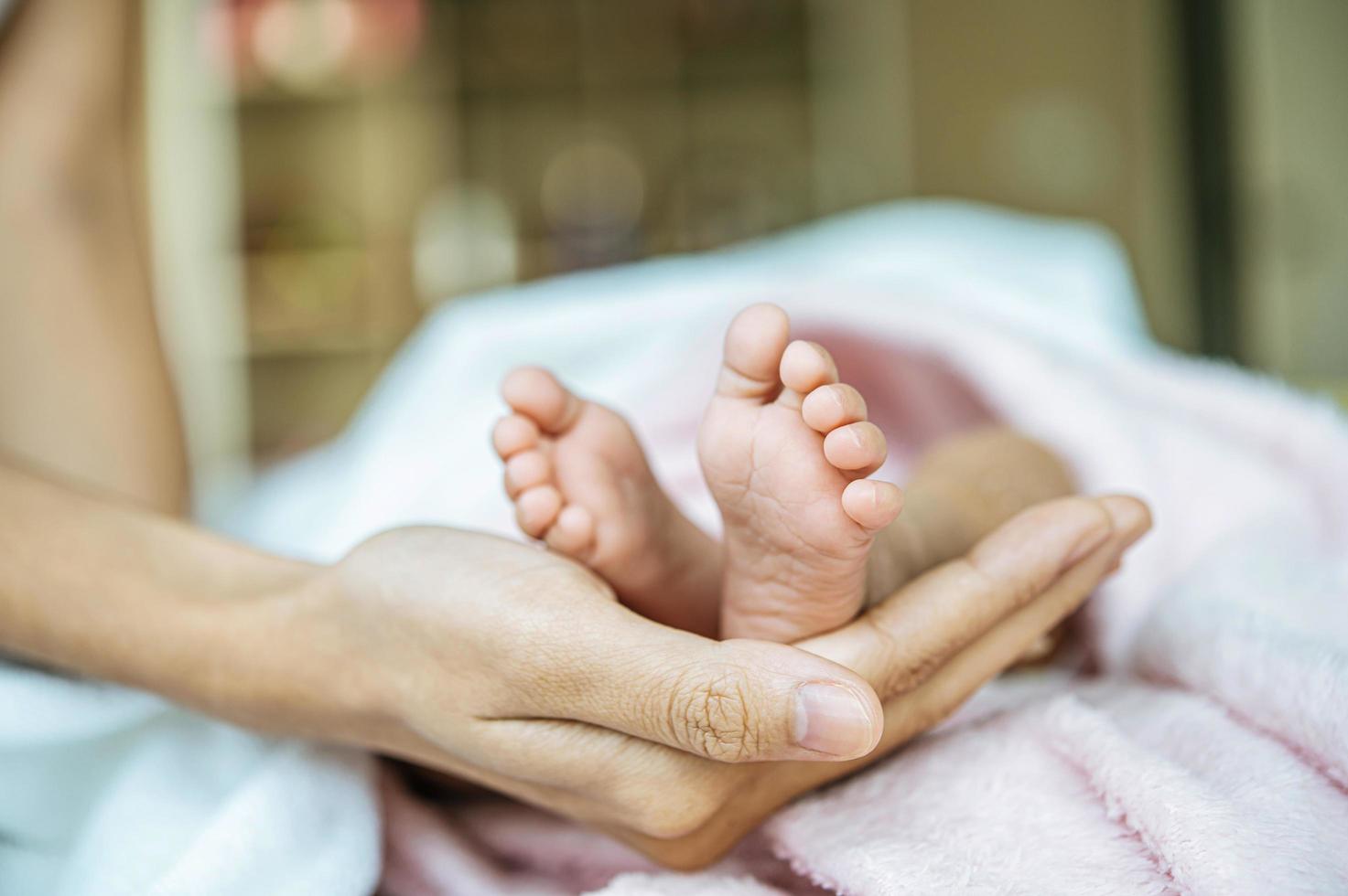 nyfödda baby fötter på mors hand foto