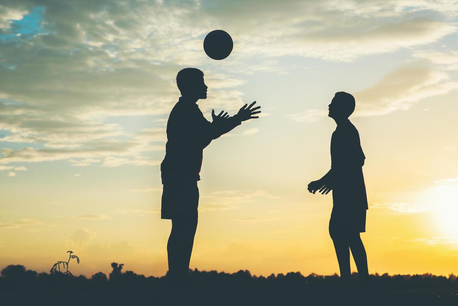 silhuett av barn som spelar fotboll fotboll foto