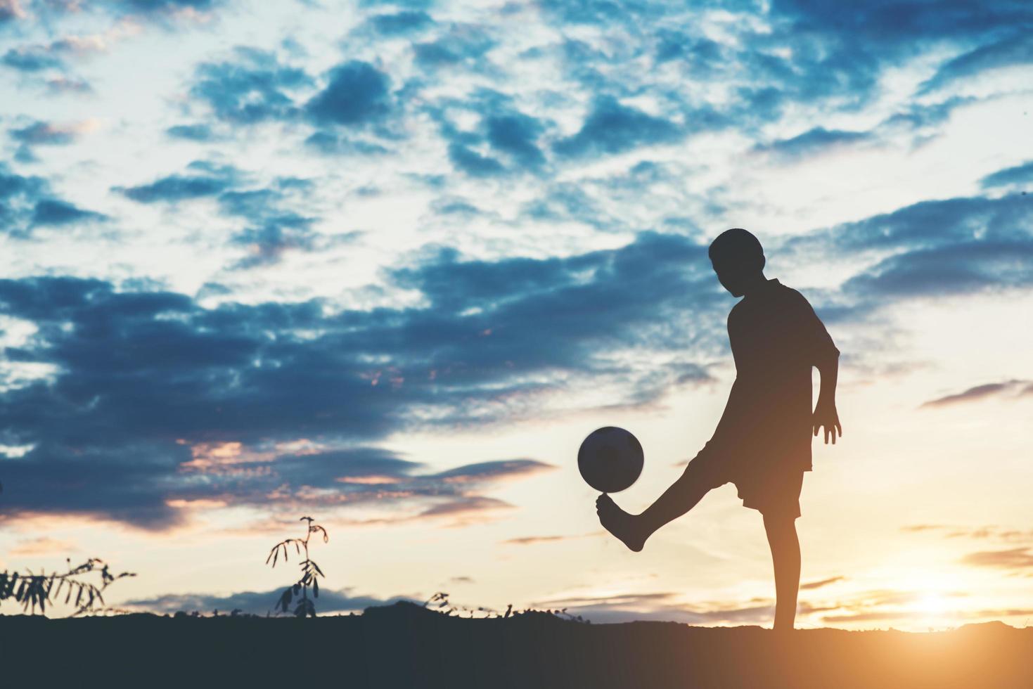 silhuett av barn som spelar fotboll fotboll foto