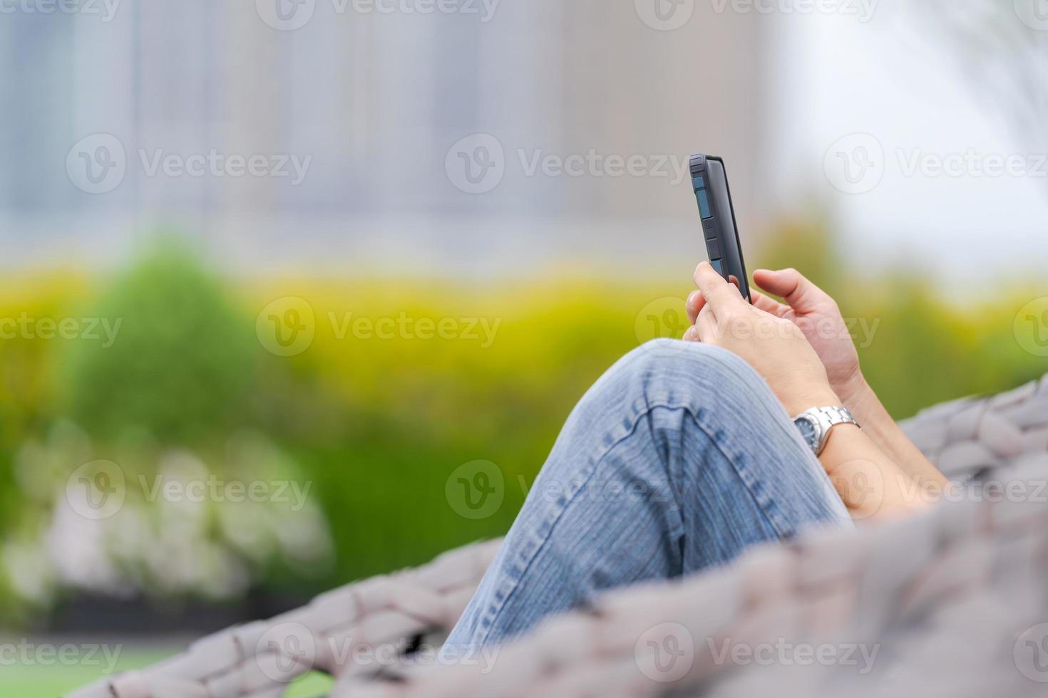 man kopplar av och använder smartphone i en stadspark foto