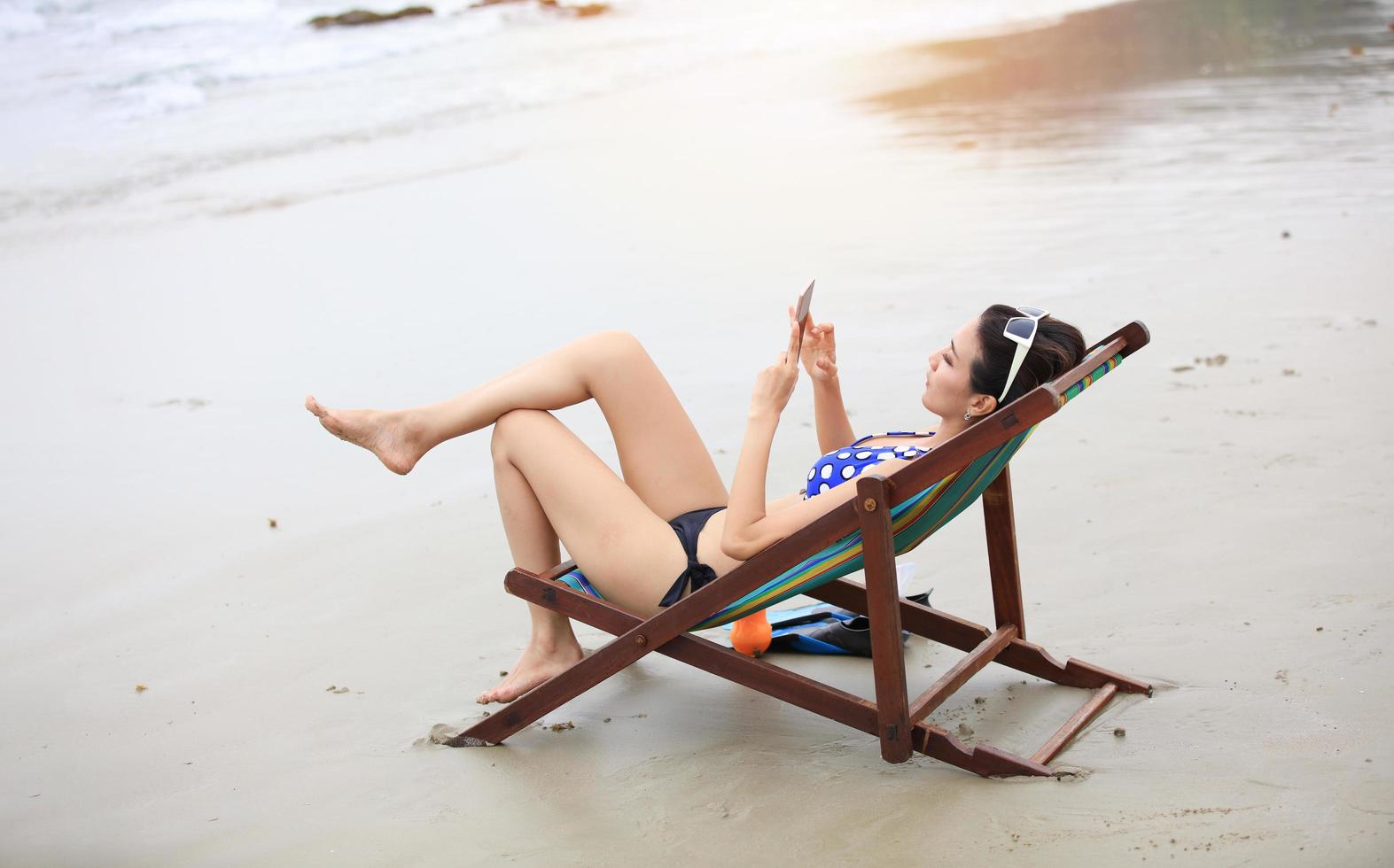 kvinna turist sitter och kopplar av under sommaren på en strand foto
