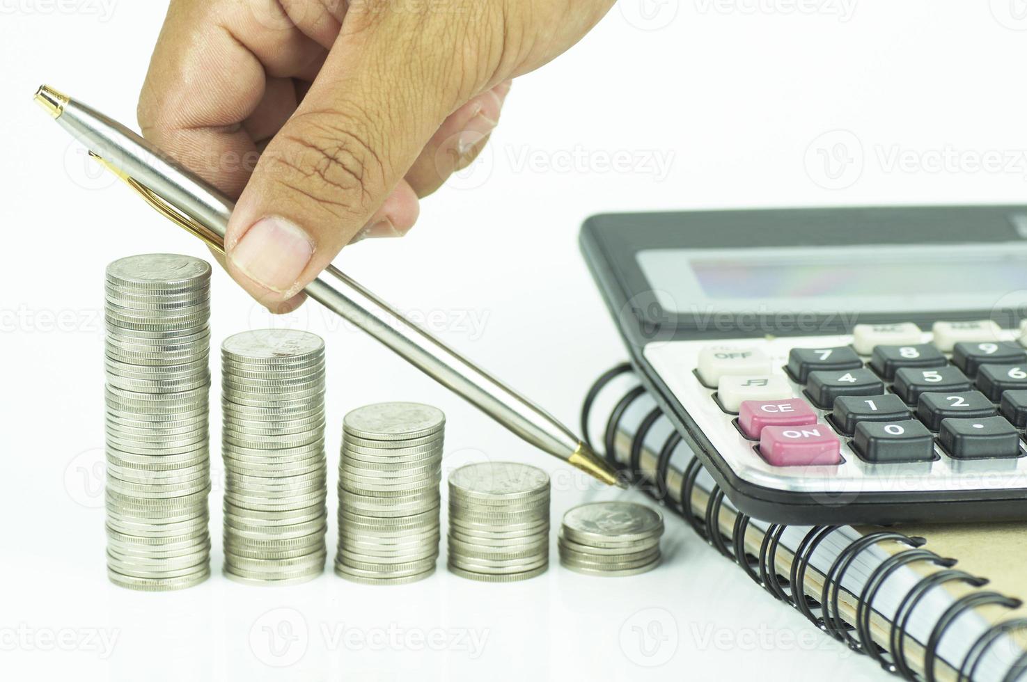penna, mynt och miniräknare på vit bakgrund foto