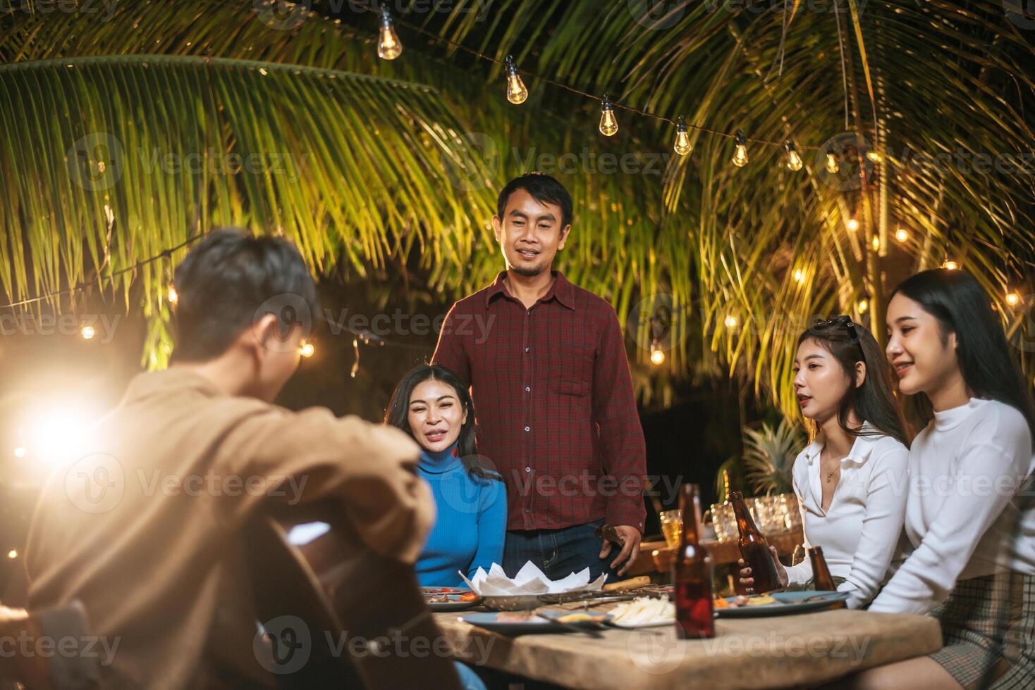 porträtt av Lycklig asiatisk grupp av vänner har roligt till musik dining och dricka tillsammans utomhus- - Lycklig vänner grupp toasting öl - människor, mat, dryck livsstil, ny år firande begrepp. foto