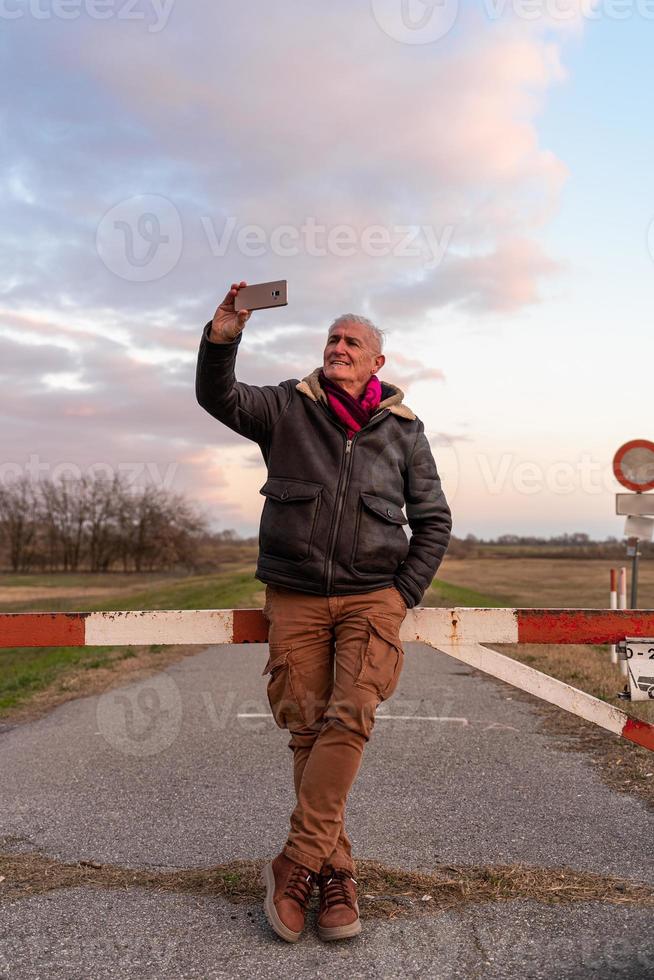 mitten åldrig man bär vinter- kläder tar en selfie i en Land väg - begrepp av människor i rekreation foto