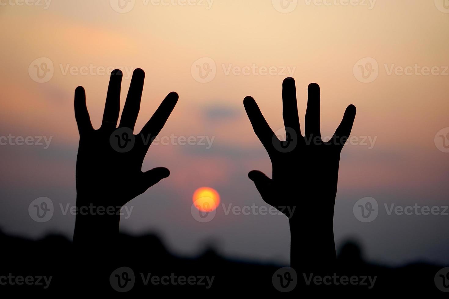silhuett av mänsklig hand Uppfostrad till göra en önskar, solnedgång bakgrund foto