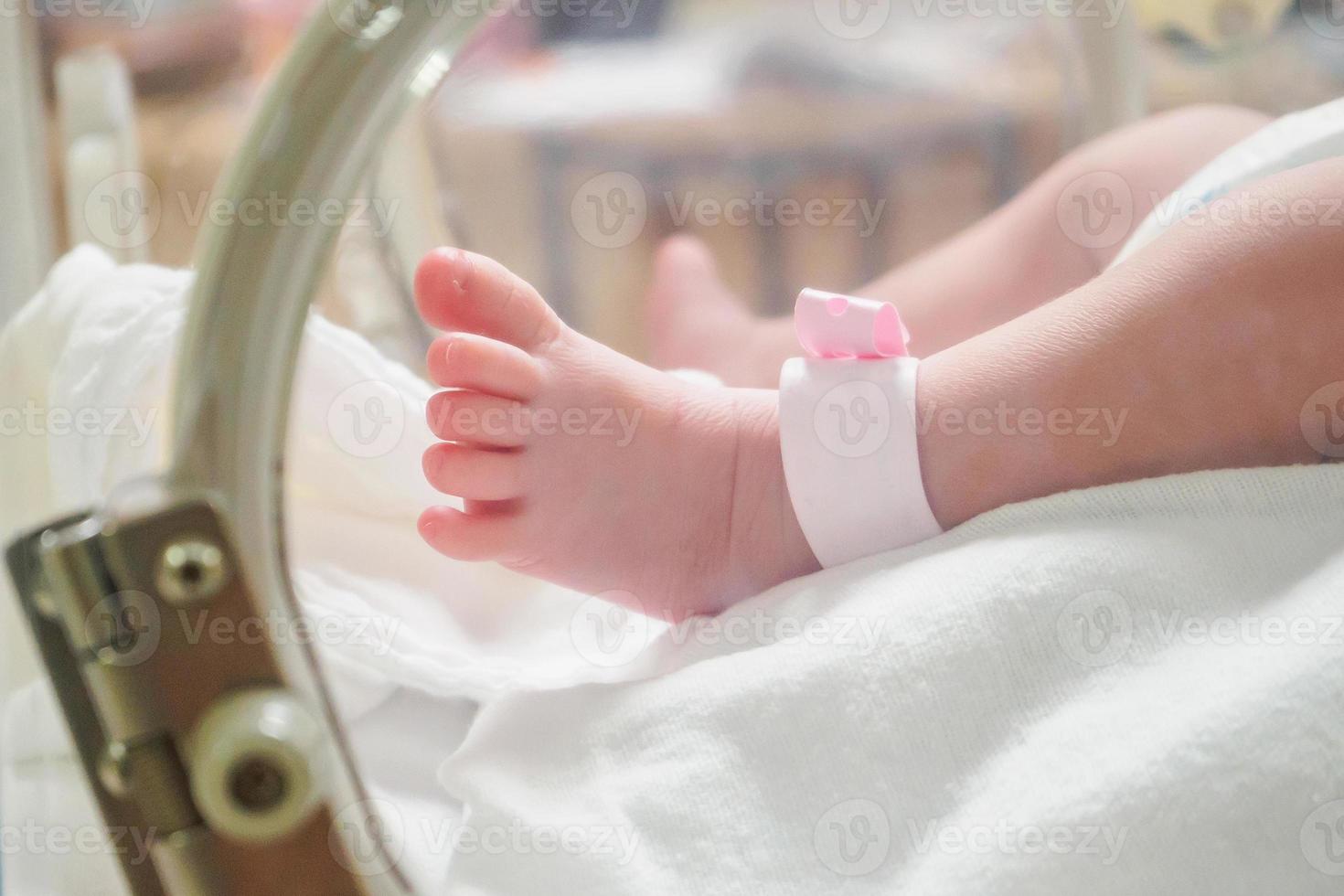 nyfödd flicka bebis inuti inkubator i sjukhus med Identifiering armband märka namn foto