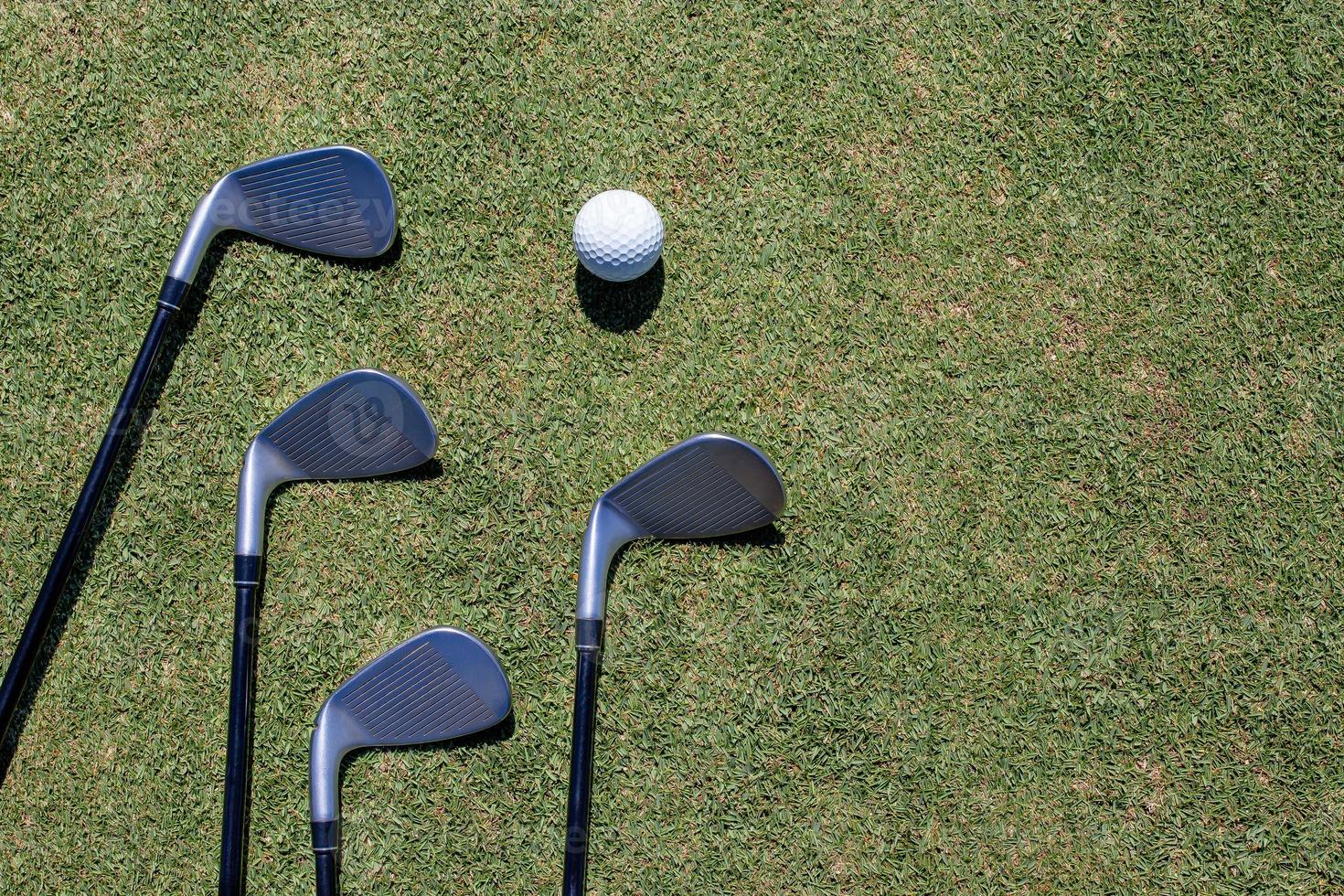 golfklubba och golfboll på grönt gräs foto