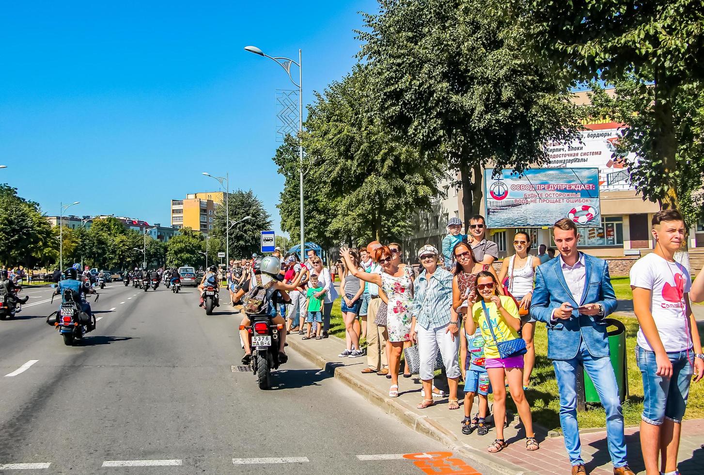 folkmassan av människor hälsar en grupp av motorcyklister på gata i stad. motorcykel parad på sommar solig dag. foto