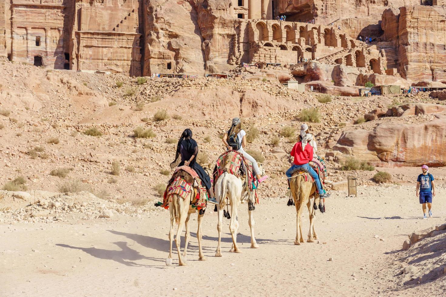 turister som rider kameler i petra, jordanien, 2018 foto