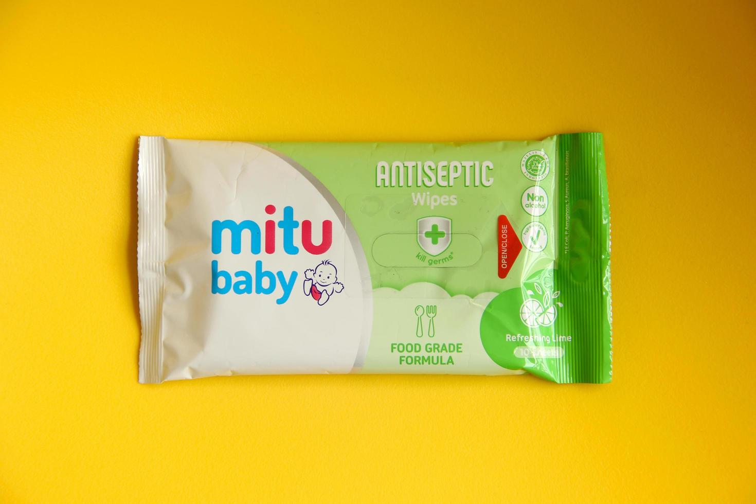 väst jakarta, indonesien - februari 10:e, 2023 - resa storlek tisu basah bebis våtservetter grön mat kvalitet i små plast förpackning. hygien produkt för barn. Foto isolerat på gul bakgrund.