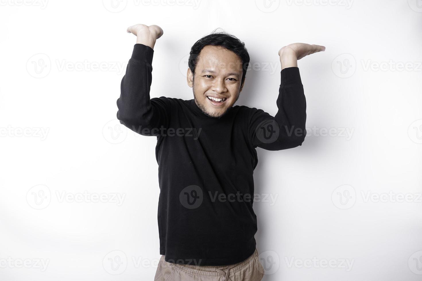upphetsad asiatisk man bär svart skjorta pekande på de kopia Plats på topp av honom, isolerat förbi vit bakgrund foto