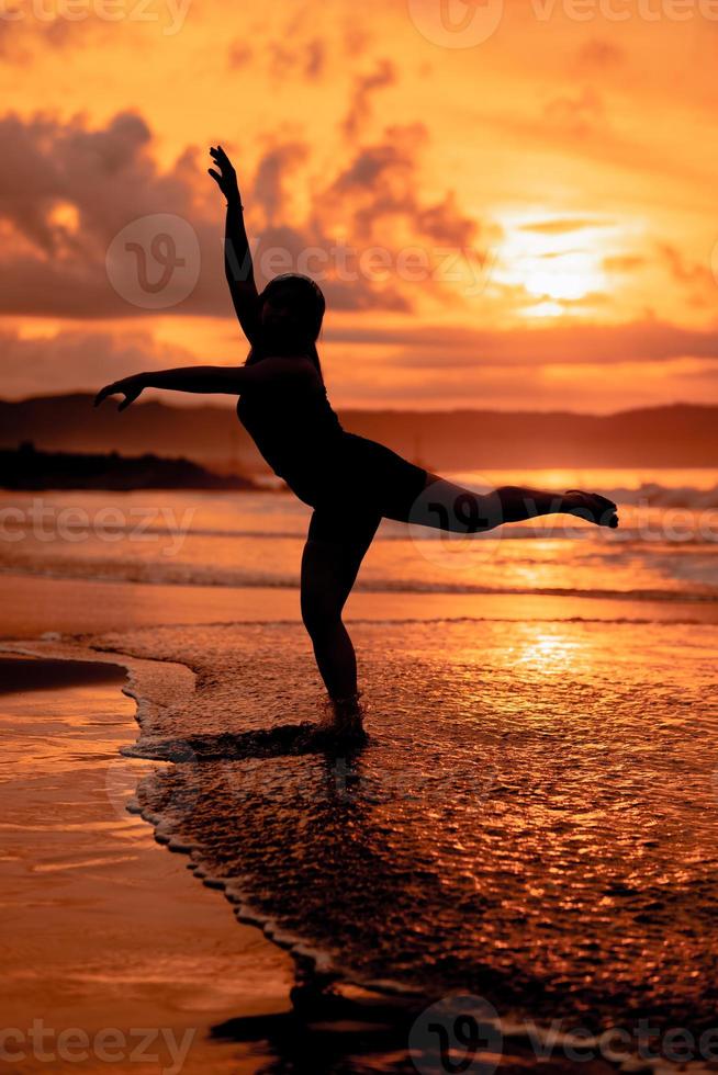 silhuett av ett asiatisk kvinna dans balett med bra flexibilitet och en se av de vågor Bakom henne foto
