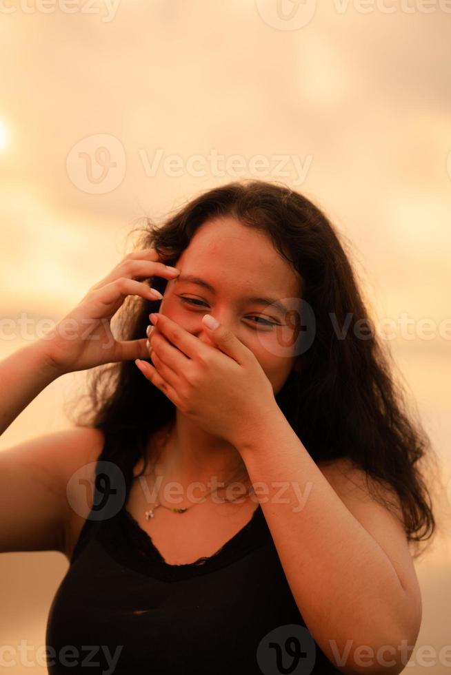 ett asiatisk kvinna poser med en djärv och sexig uttryck medan bär svart kläder i främre av de strand foto