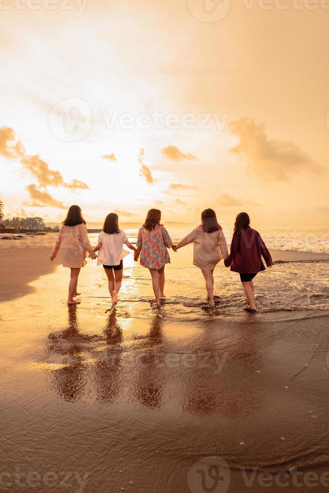 en grupp av asiatisk kvinnor är löpning med deras vänner lyckligt på de strand foto