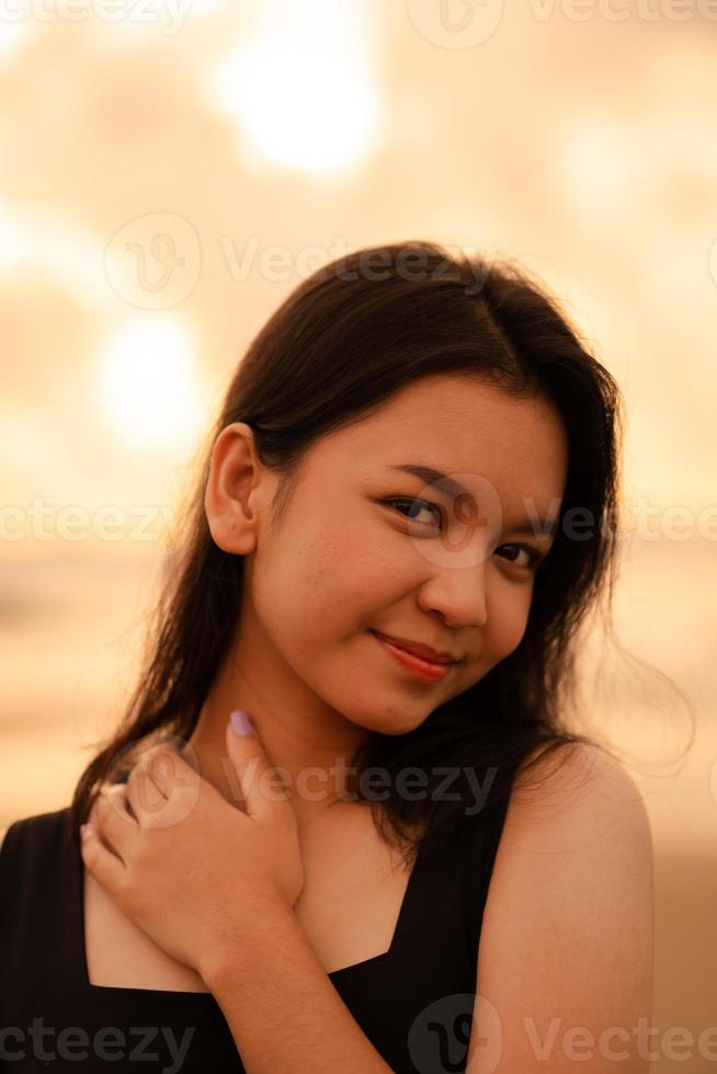 ett asiatisk Tonårs kvinna med en svart skjorta och svart hår har en söt ansikte när hon ler och åtnjuter de se foto