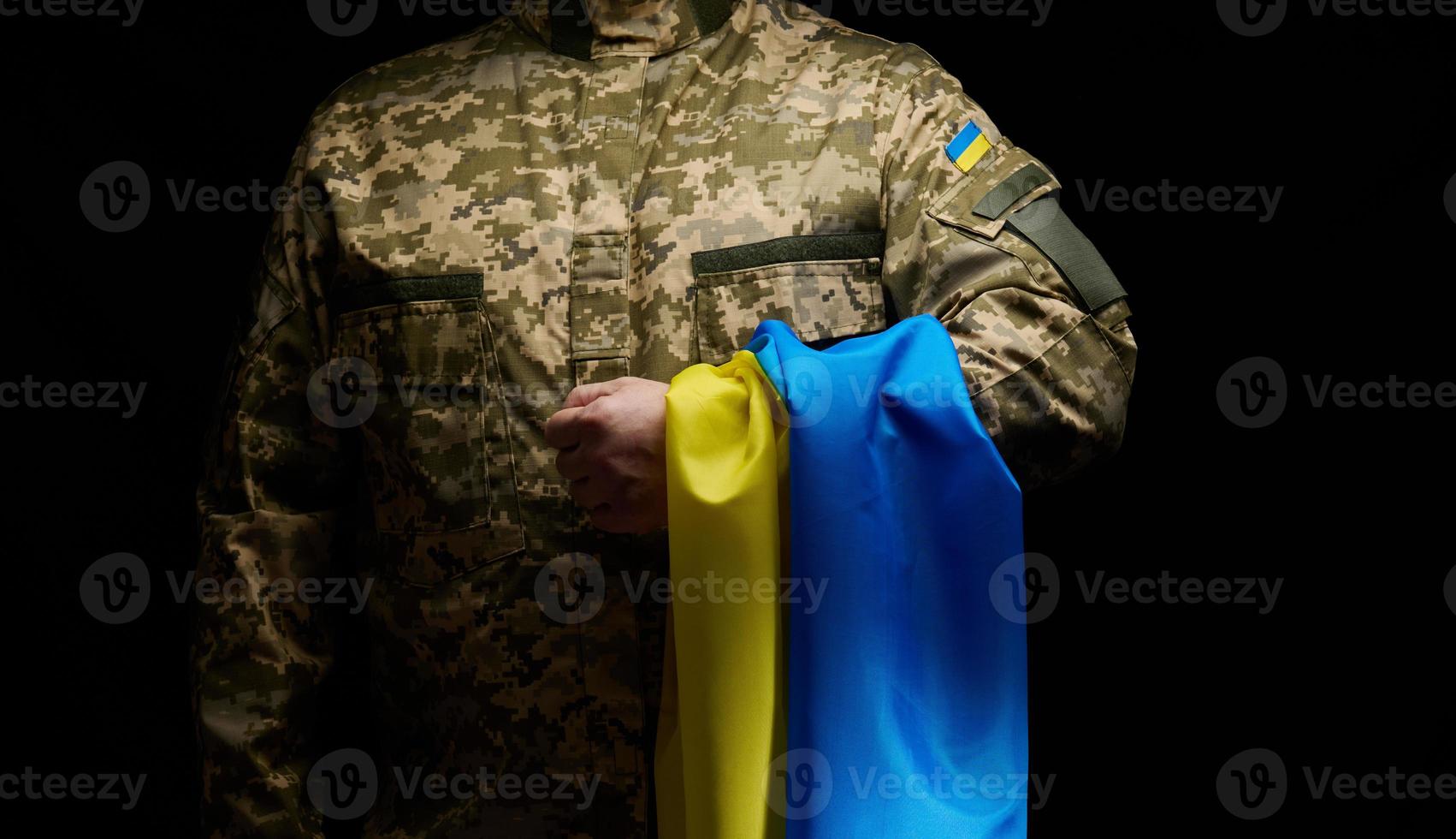 en soldat av de ukrainska väpnad krafter står med en blå-gul flagga av ukraina på en svart bakgrund. uppfyllande veteraner och minnesmärke de där dödade i de krig foto