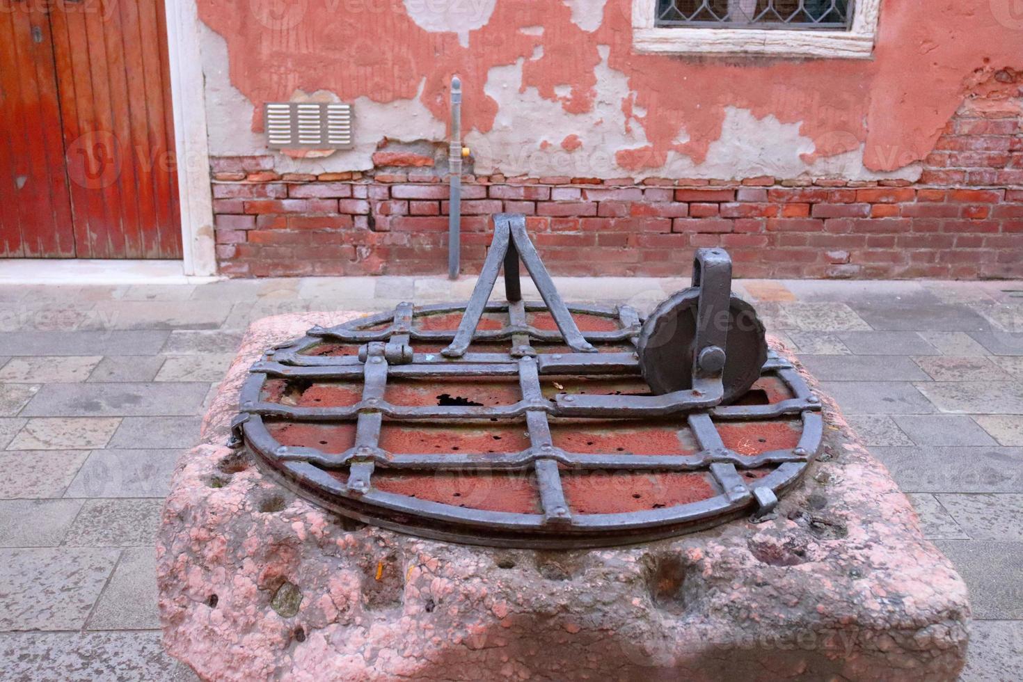 stänga upp gammal vatten väl med järn grill i Italien. gata scen, gammal vägg. foto
