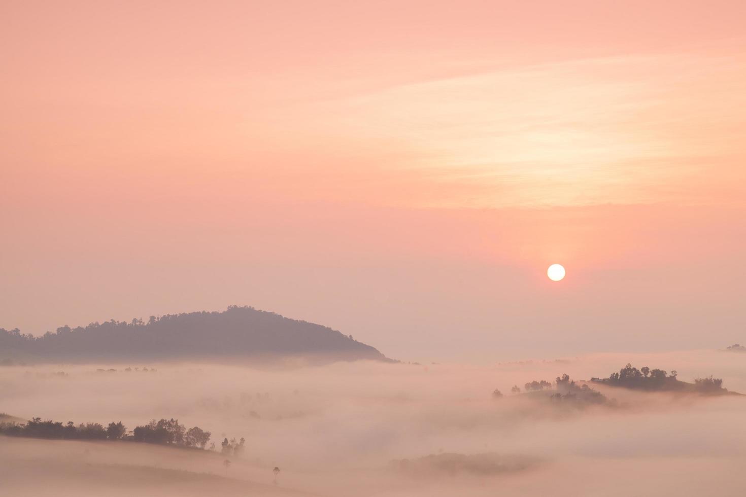 dimma täckta berg och den stigande solen foto