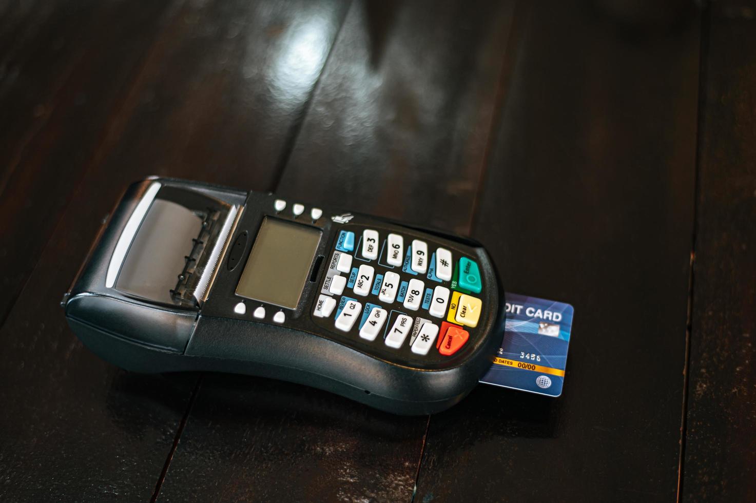 kreditkortsmaskin med insatt kreditkort på träbord foto