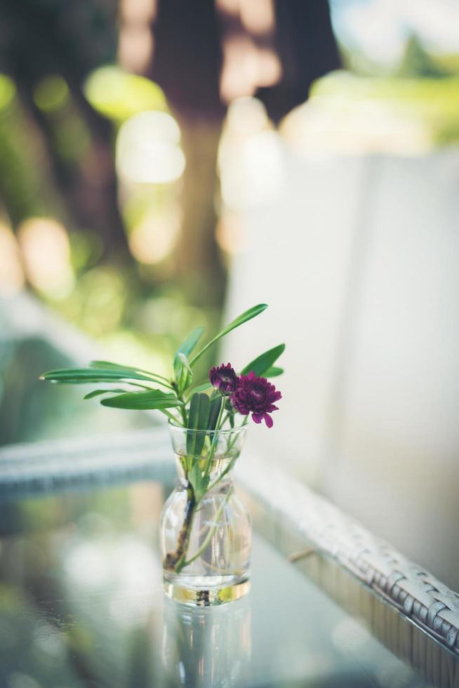 lila blommor i en vas på ett bord utomhus foto