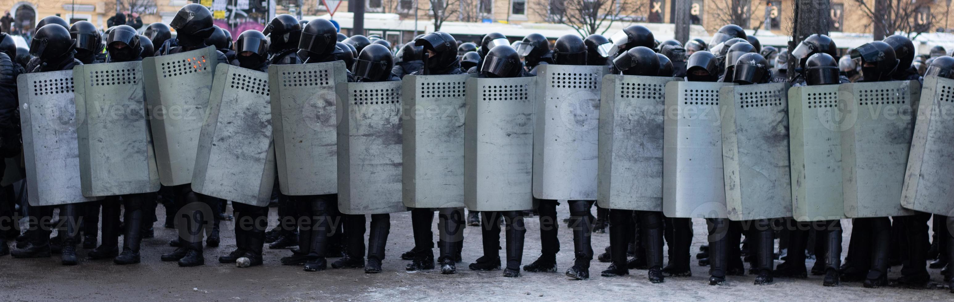 linje av polis upplopp krafter, protest i stad. enhetlig rustning med sköldar foto