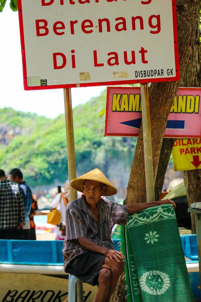 yogyakarta, indonesien i november 2022. Foto av en farfar eller gammal man hyra mattor på baron strand.