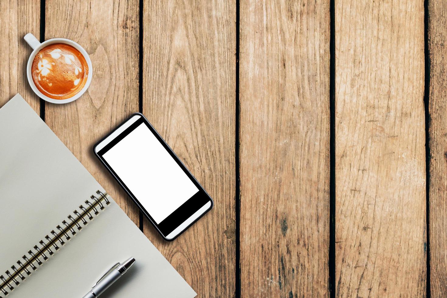 smartphone kaffe kopp och anteckningsbok på trä- bakgrund med Plats. foto
