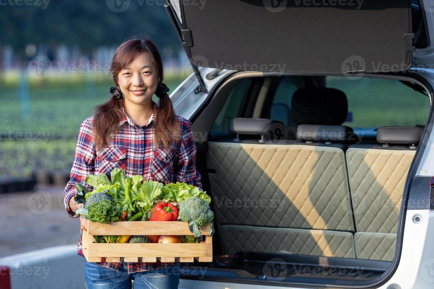 asiatisk jordbrukare är leverera nyligen skörda av organiska ämnen vegetabiliska låda in i de kund trunk bil för stödjande lokal- företag begrepp foto