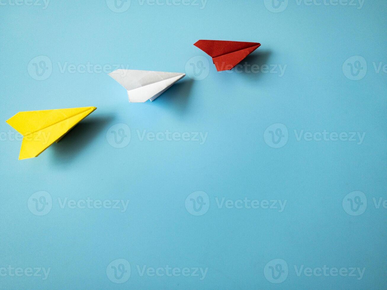 röd papper flygplan origami ledande vit och gul flygplan på blå bakgrund med anpassningsbar Plats för text. ledarskap Kompetens begrepp. foto