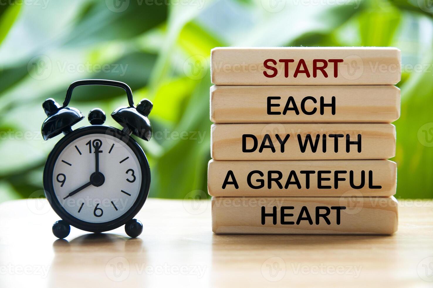 Start varje dag med en tacksam hjärta text på trä- block med larm klocka och natur bakgrund. motiverande begrepp foto