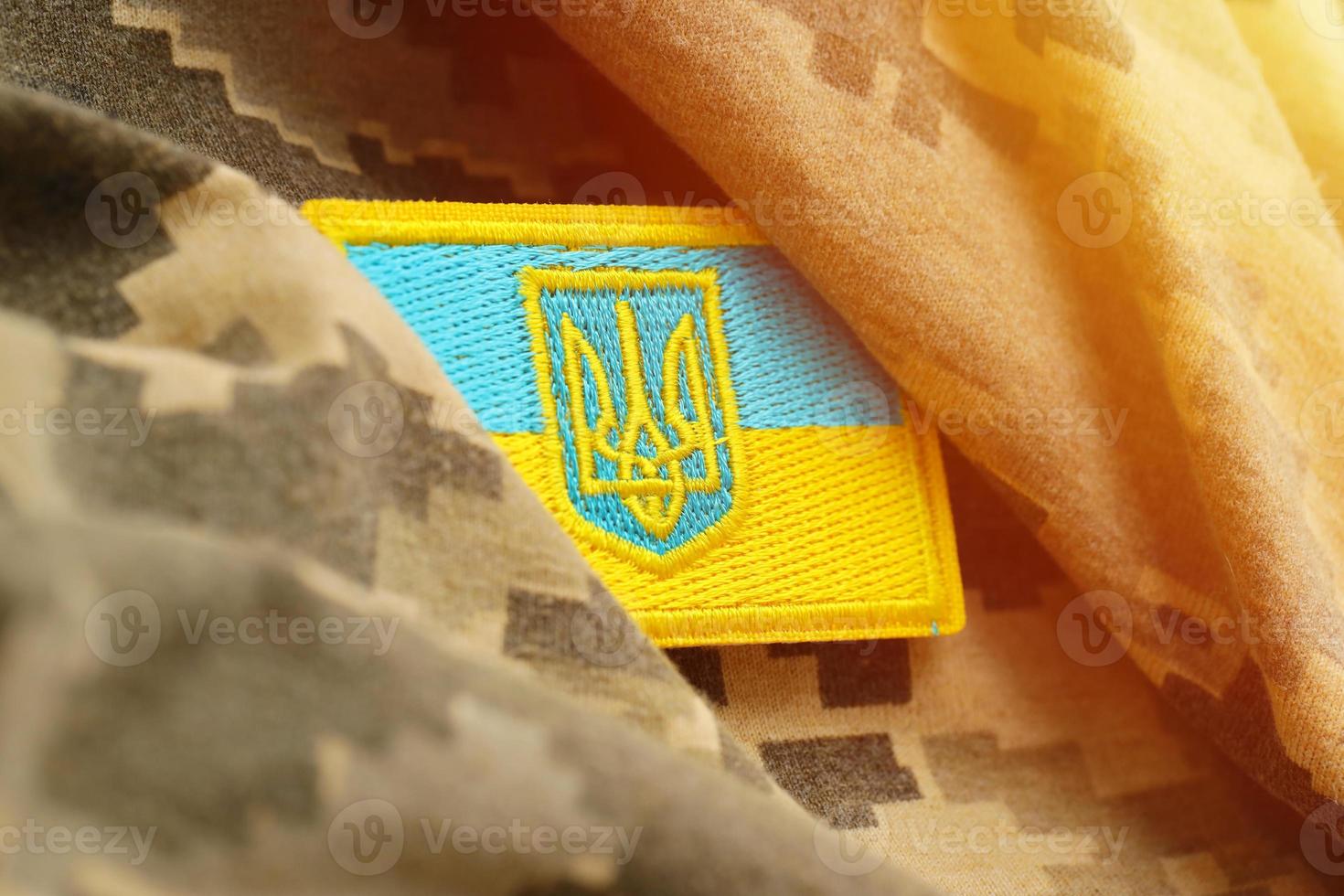 militär kamouflage tyg med ukrainska flagga på enhetlig sparre foto