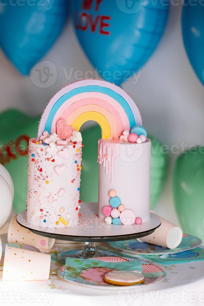 stor födelsedag kaka med regnbåge, färgrik strössel. på många färgrik hjärta ballonger bakgrund. födelsedag fest. ljuv Semester. foto