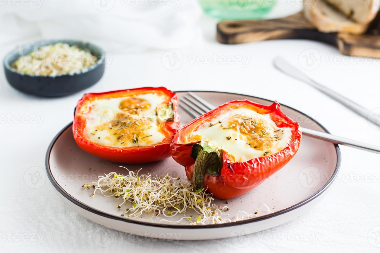 klocka peppar halvor bakad med ägg och mikrogrönsaker på en tallrik på de tabell. flexitär organisk diet foto