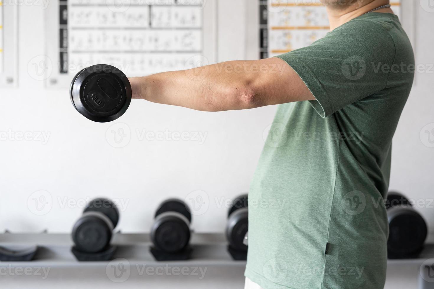 man träna i de inomhus- Gym, man lyft upp en hammare ringla vikt träning. bodybuilding hantlar i Gym. Träning i kondition Gym. foto