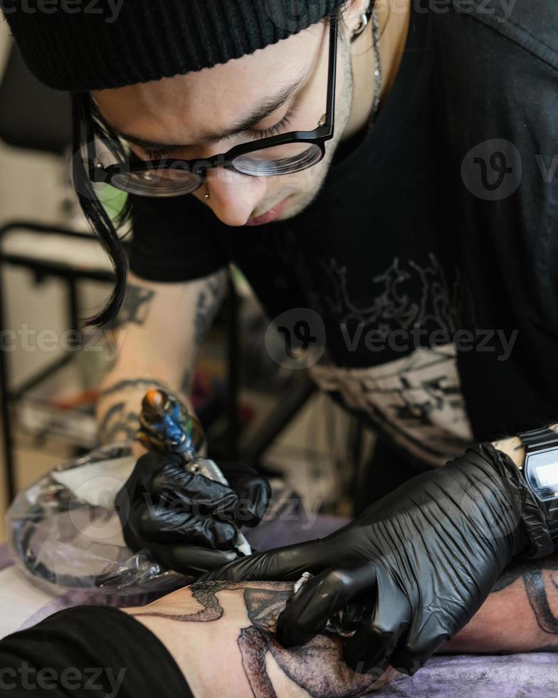 professionell tatuering konstnär saker en tatuering på de mannens hand. tatuering konstnär på arbete. tatuering skapande bearbeta. konst och kreativitet foto