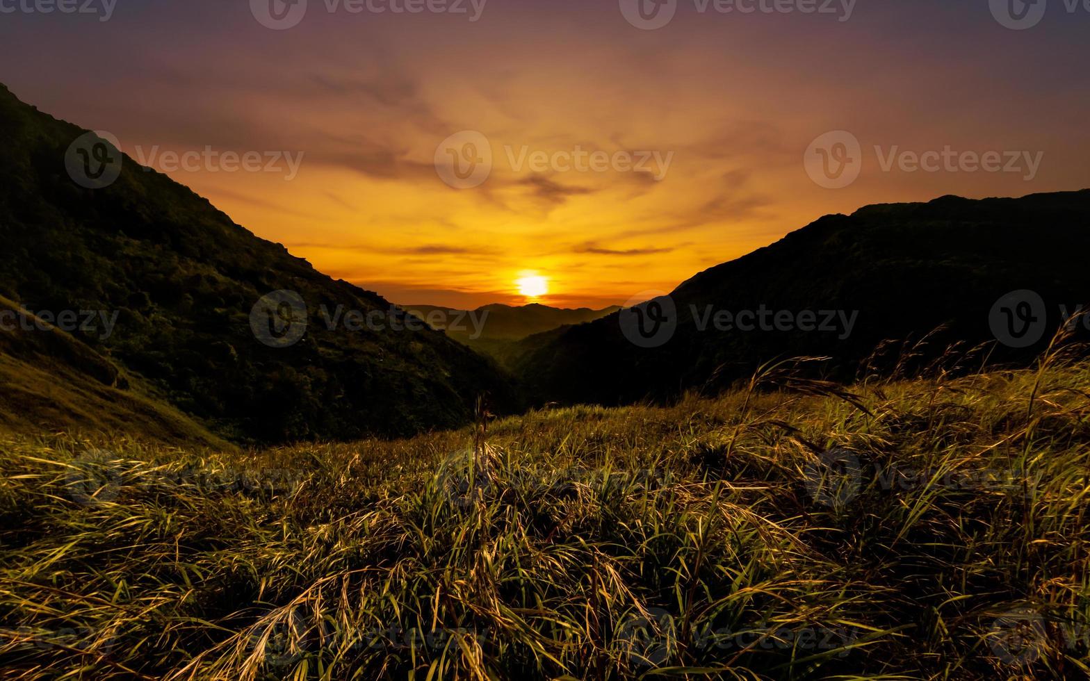 skön berg solnedgång panorama med gräsmark foto