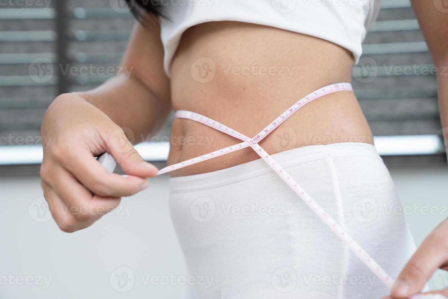 begrepp av vikt förlust. flicka innehar jeans i henne hand och visar en tunn midja och åtgärder henne midja med en centimeter. diet begrepp foto