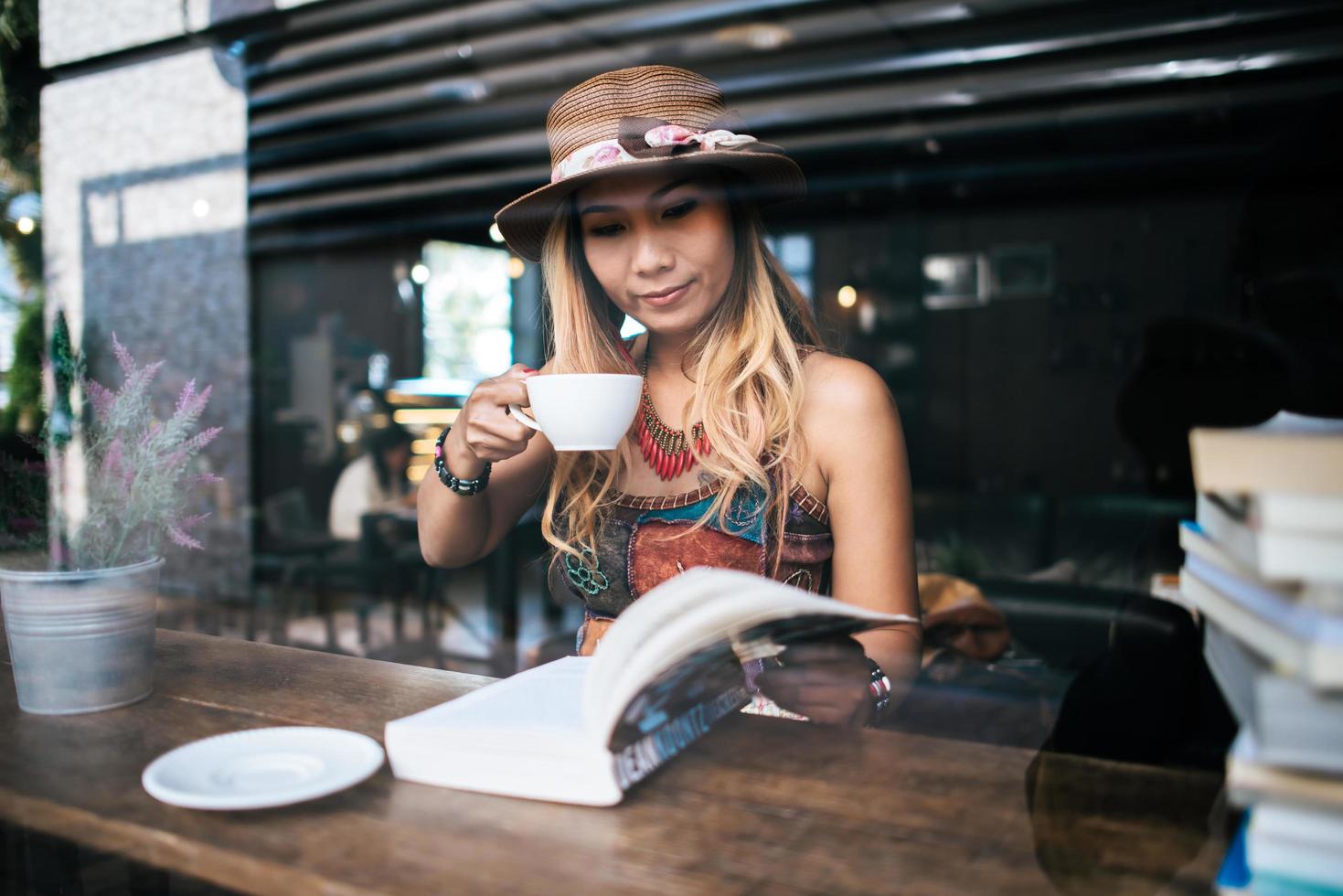 kvinna som dricker cappuccino och läser en bok foto