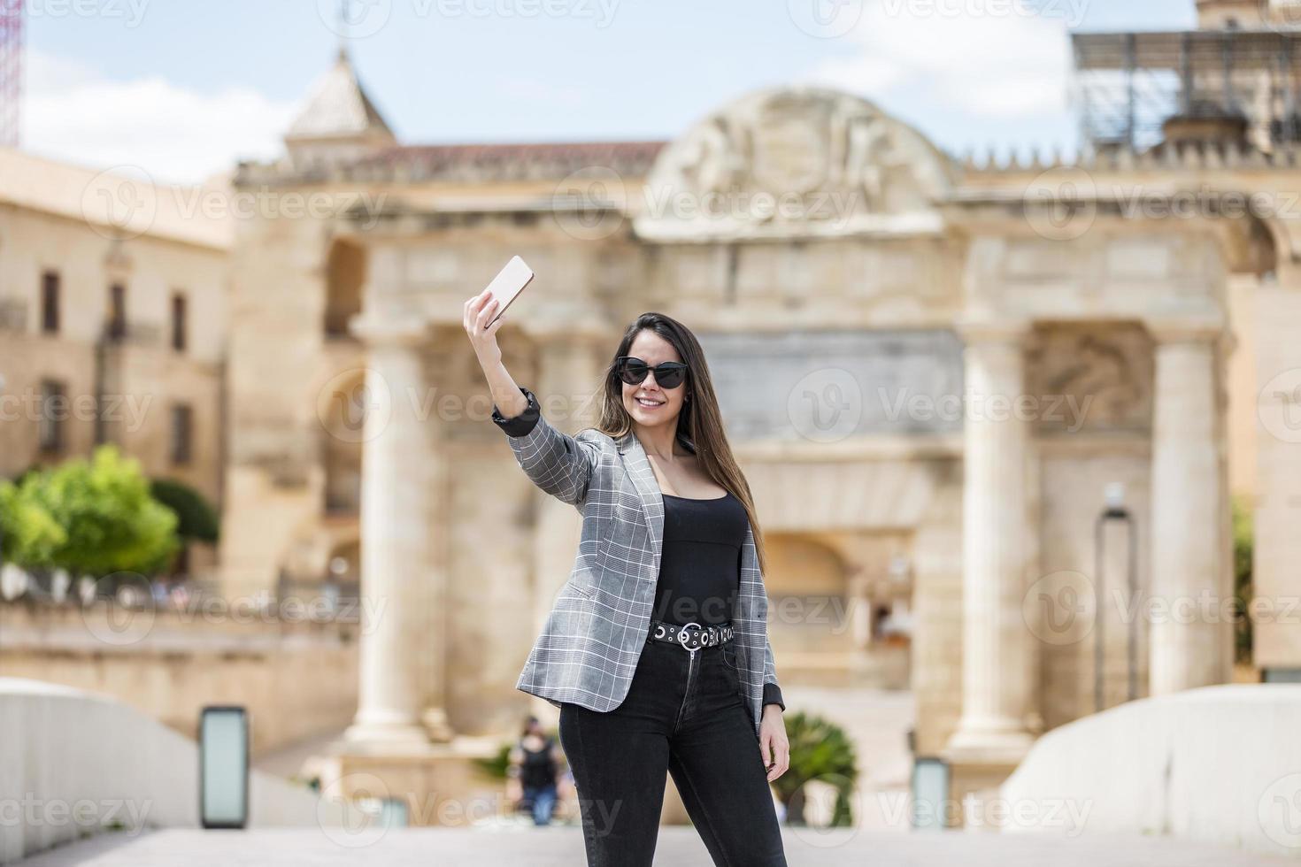 Lycklig kvinna tar selfie mot historisk byggnad foto