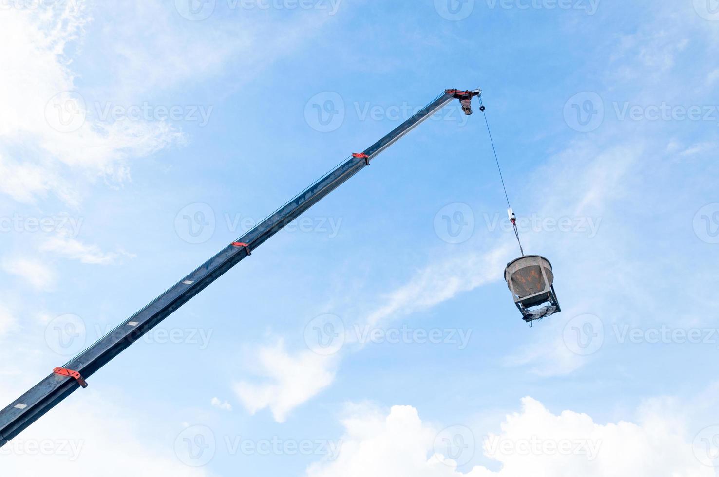 cement eller betong hink hängande på tråd på konstruktion webbplats med blå himmel bakgrund foto