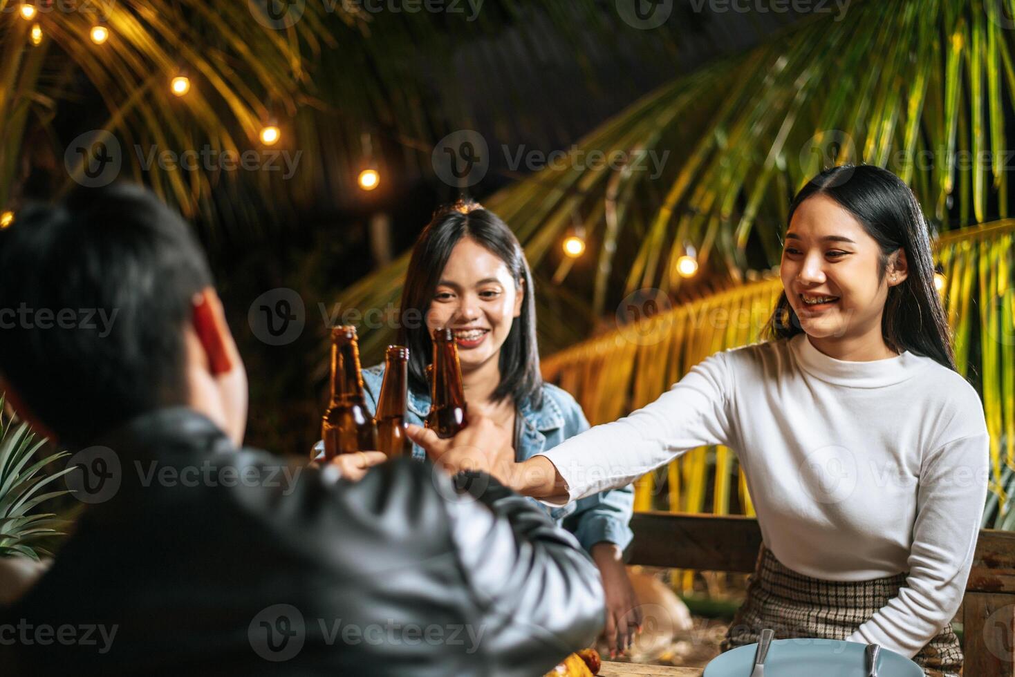 porträtt av Lycklig asiatisk vänner har middag fest tillsammans - ung människor Sammanträde på bar tabell toasting öl glasögon middag utomhus- - människor, mat, dryck livsstil, ny år firande begrepp. foto