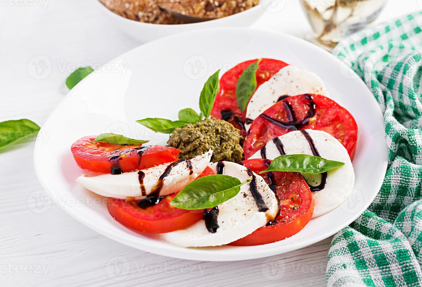 traditionell italiensk caprese sallad med mozzarella, tomat, basilika och balsamisk vinäger foto