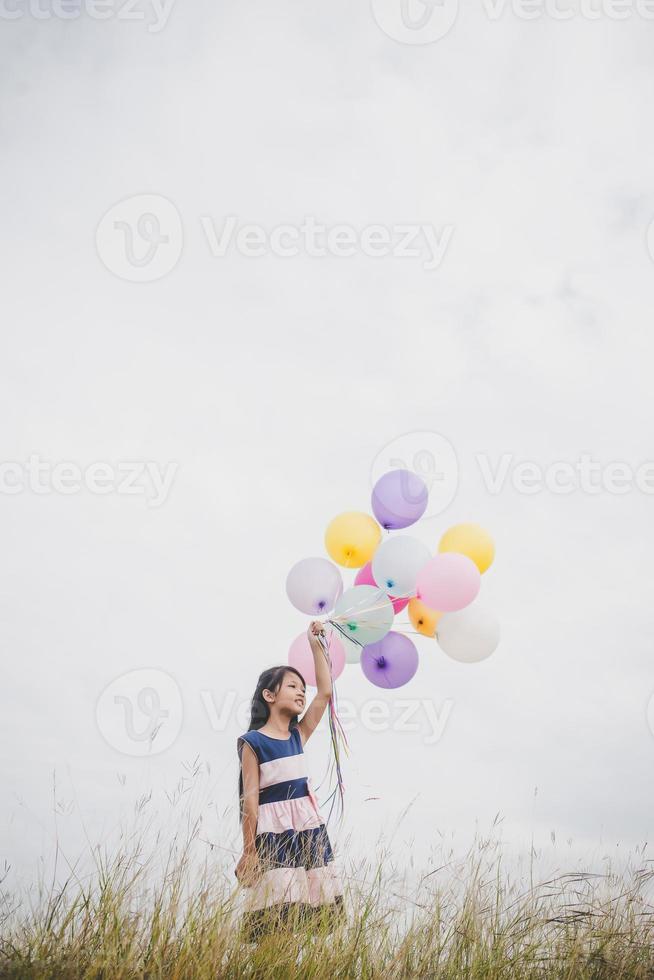 liten flicka som leker med ballonger på ängfältet foto