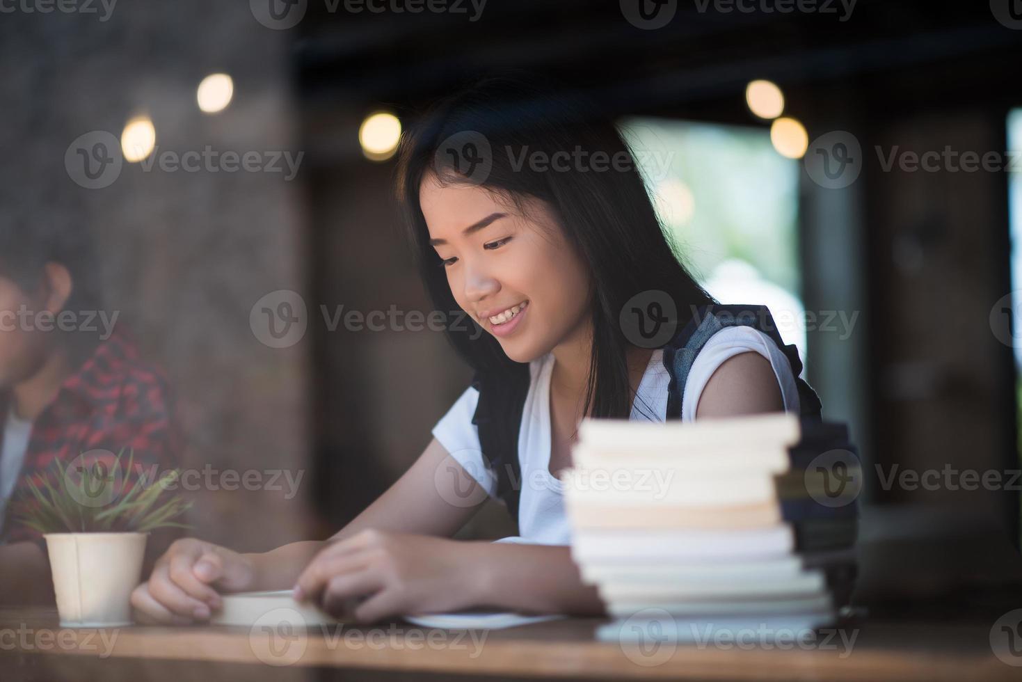 ung kvinna som läser bok sitter inomhus i ett stadscafé foto