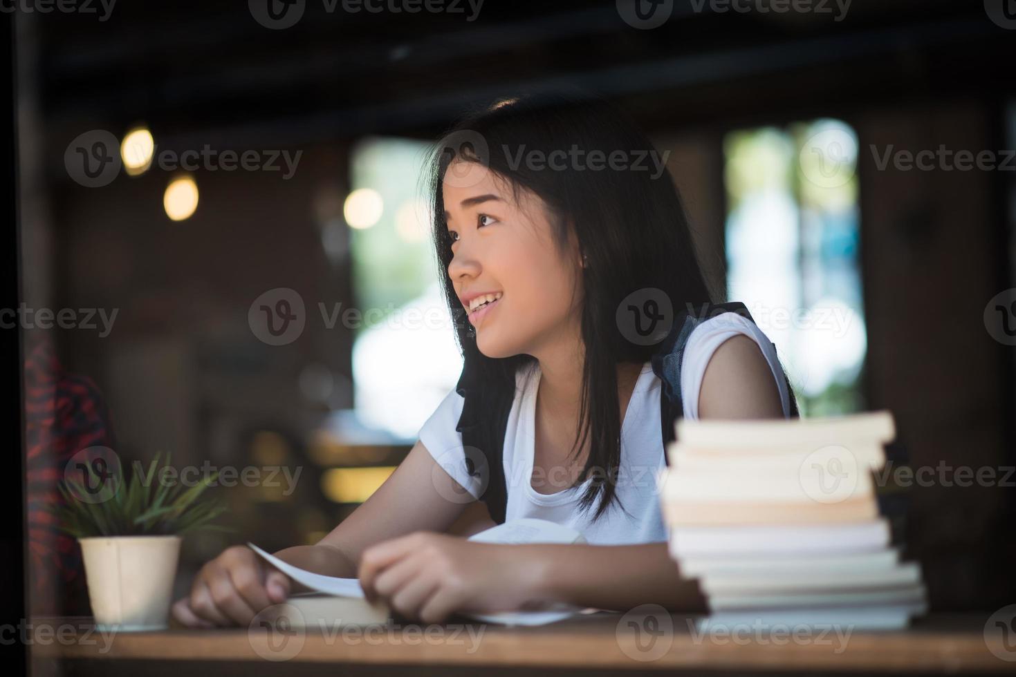 ung kvinna som läser bok sitter inomhus i ett stadscafé foto