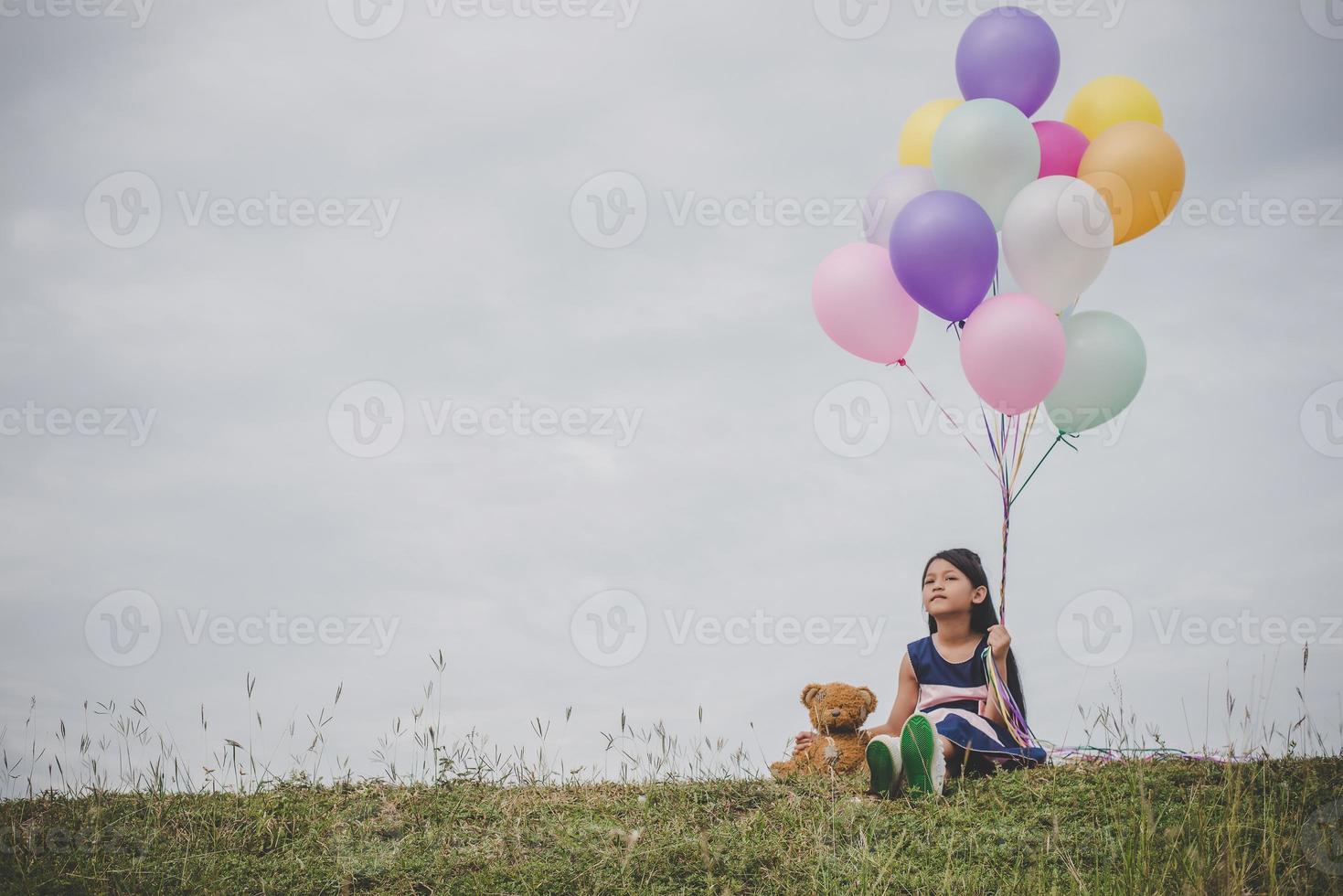 liten flicka som leker med ballonger på ängfältet foto